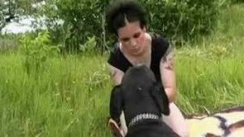 Brunette and black dog make love during outdoor picnic